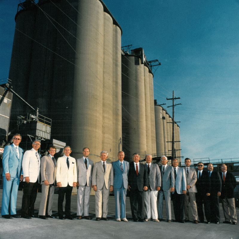 Company leadership in front of silos in the 1980s