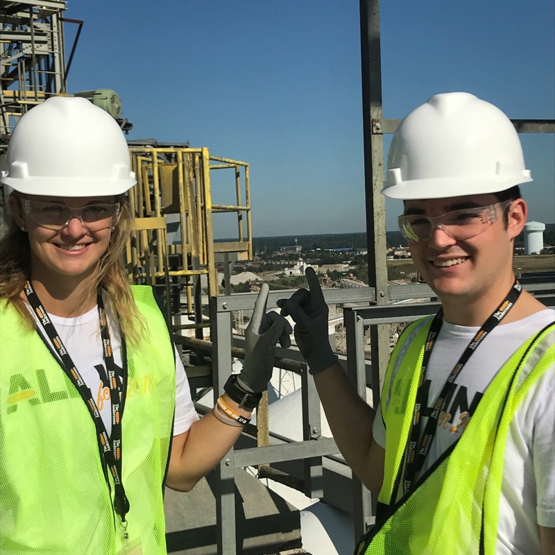 Two interns in hard hats and safety gear on-site at an operations location