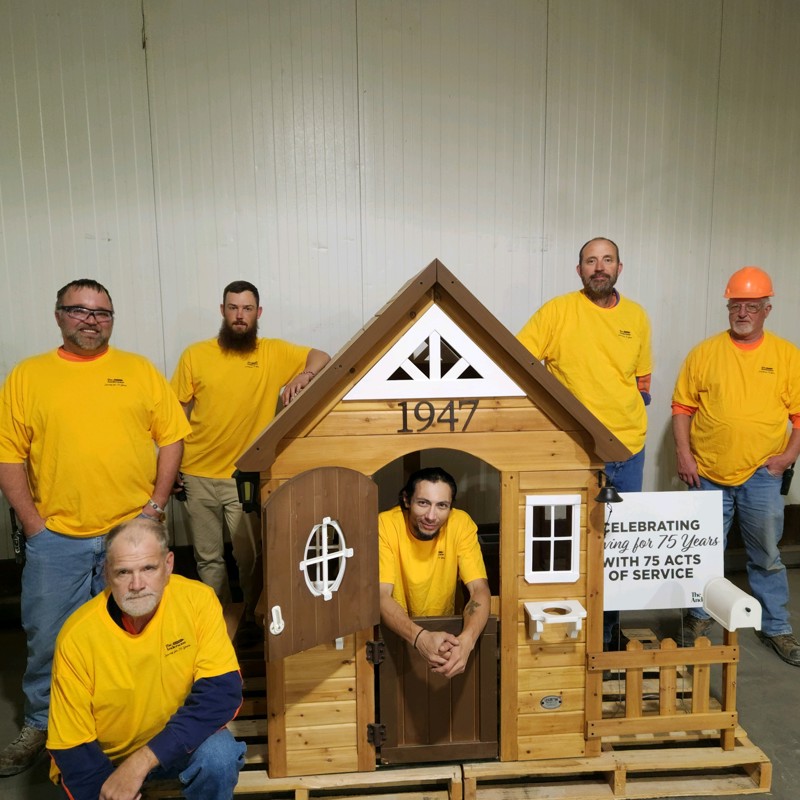 Employees in yellow shirts with kids playhouse