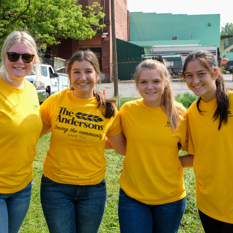 Four people standing together smiling 