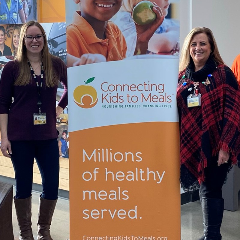 Individuals with a banner for the organization "Connecting Kids to Meals" 