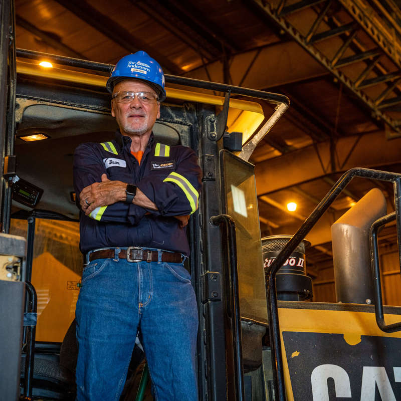 Individual standing on a front loader equipment vehicle at an ethanol plant