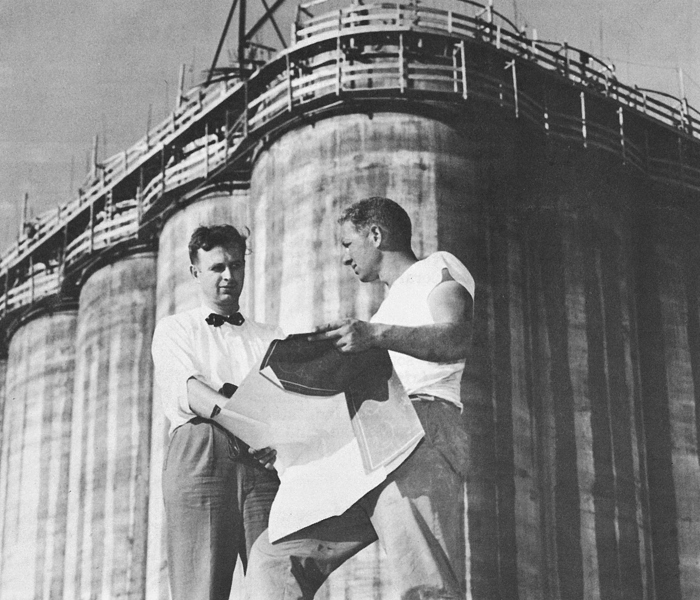 Two individuals in front of The Big Pour silos