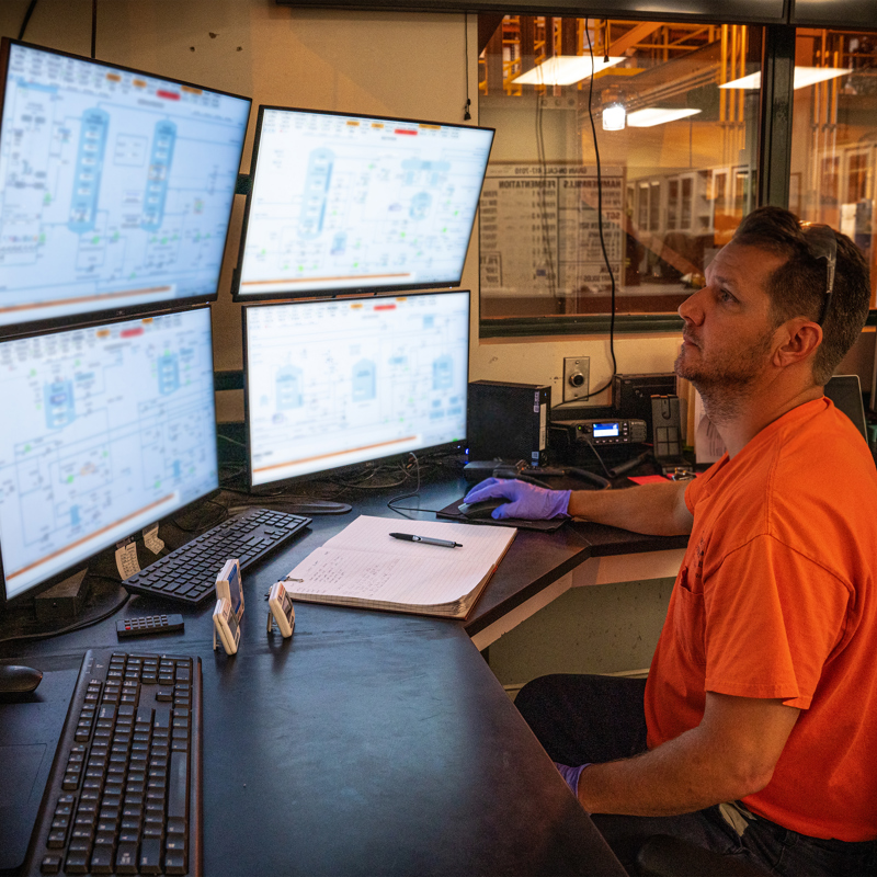 Individual at an ethanol plant control desk, working with several computer monitor screens